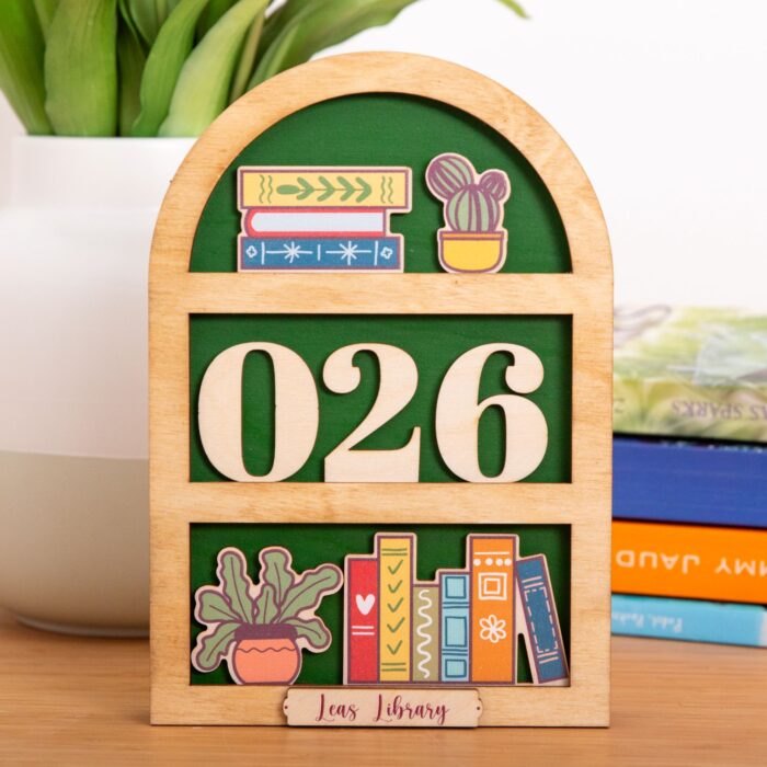 Handgefertigter Bücher-Tracker aus hellem Holz in Arch-Form mit Blumen-Print, einsteckbaren Zahlen und praktischem Aufbewahrungsfach auf der Rückseite.