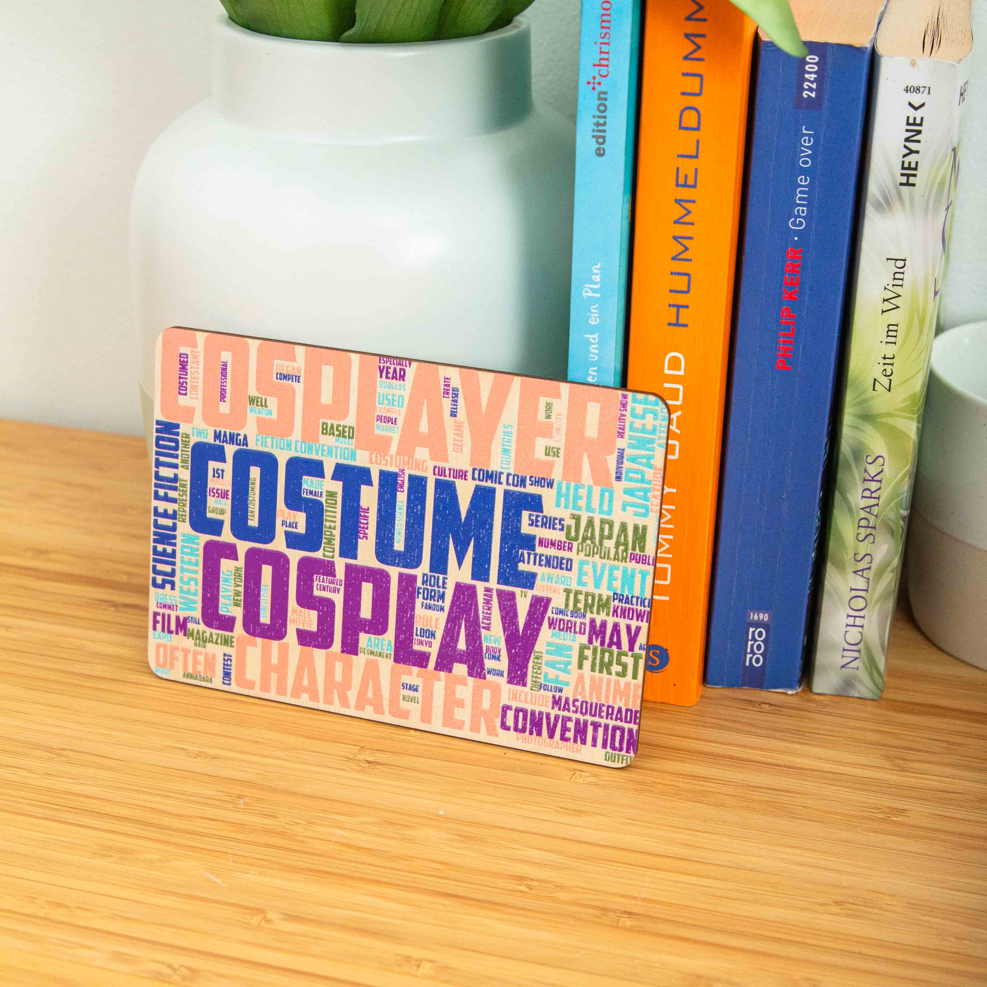 Postkarte Cosplay / Holzpostkarte Bücherliebhaber / Bookstagram / Postkarten mit Botschaft 4 Eine rechteckige Holzpostkarte im Querformat. Im Zentrum stechen vier Begriffe in sehr großen, strukturierten Großbuchstaben hervor: „COSPLAYER“ in Lachsrosa ganz oben, „COSTUME“ in Dunkelblau darunter, gefolgt von „COSPLAY“ in Lila und „CHARACTER“ in hellem Orange am unteren Rand. Die Zwischenräume und Ränder sind dicht mit kleineren, zugehörigen englischen Begriffen wie „Manga“, „Anime“, „Convention“, „Japan“ und „Science Fiction“ in verschiedenen Farben und Ausrichtungen gefüllt.
