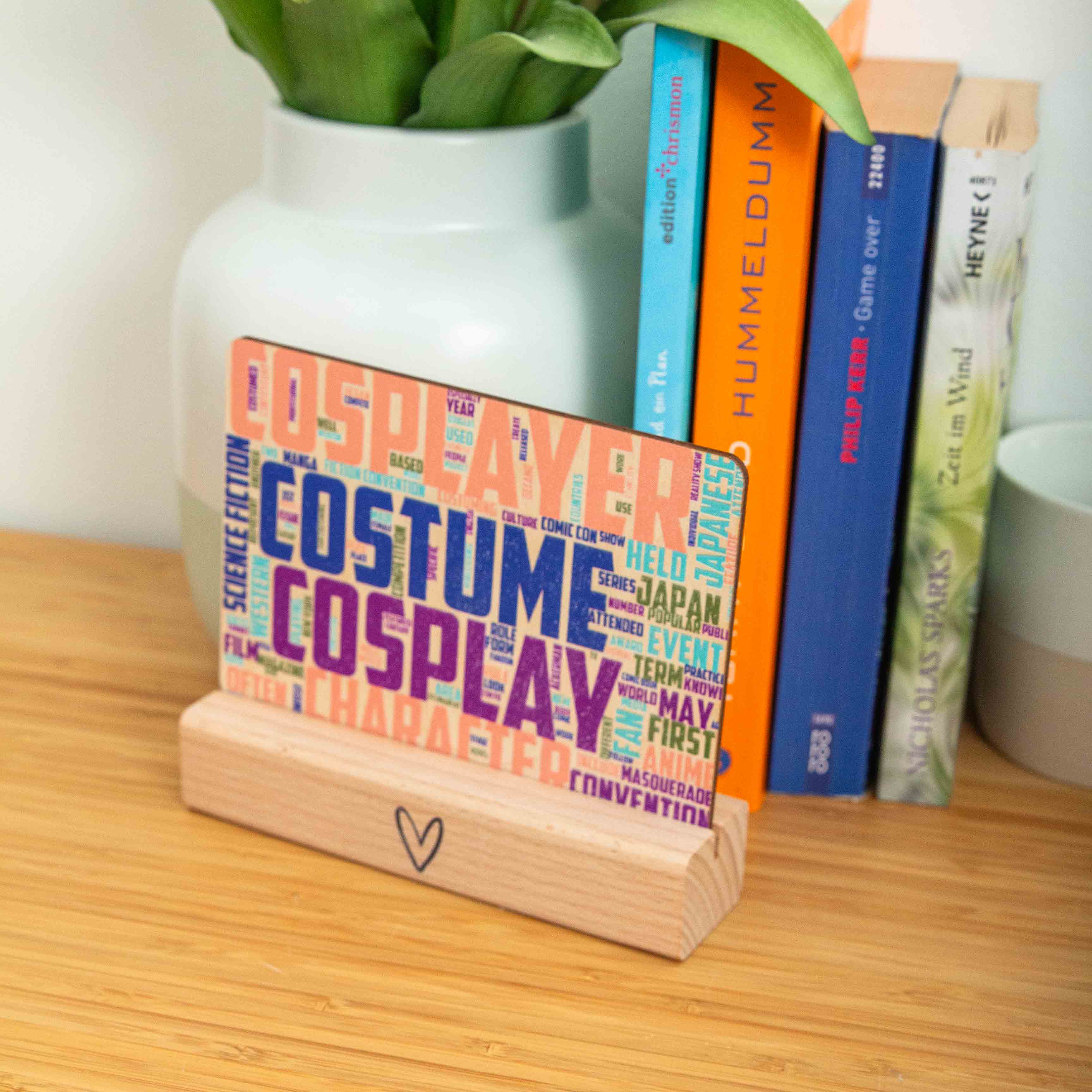 Postkarte Cosplay / Holzpostkarte Bücherliebhaber / Bookstagram / Postkarten mit Botschaft 3 Eine rechteckige Holzpostkarte im Querformat. Im Zentrum stechen vier Begriffe in sehr großen, strukturierten Großbuchstaben hervor: „COSPLAYER“ in Lachsrosa ganz oben, „COSTUME“ in Dunkelblau darunter, gefolgt von „COSPLAY“ in Lila und „CHARACTER“ in hellem Orange am unteren Rand. Die Zwischenräume und Ränder sind dicht mit kleineren, zugehörigen englischen Begriffen wie „Manga“, „Anime“, „Convention“, „Japan“ und „Science Fiction“ in verschiedenen Farben und Ausrichtungen gefüllt.